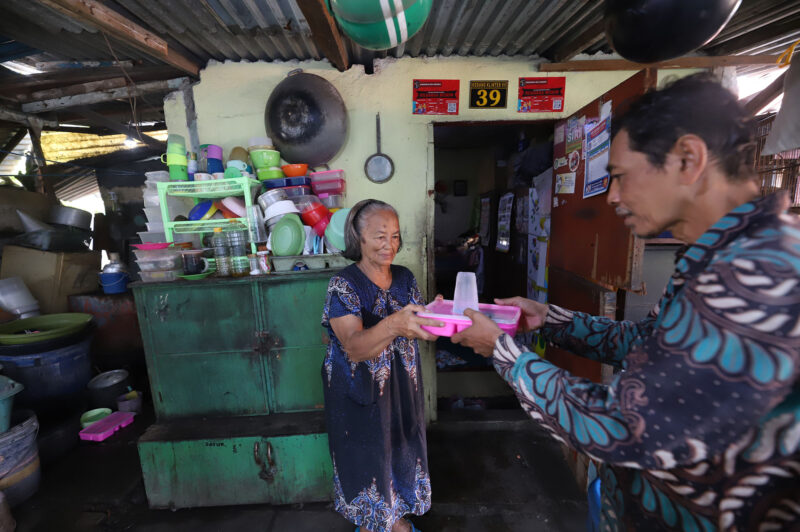 Petugas dari Dinas Sosial memberikan saat membagikan  makanan ke penerima manfaat permakanan (Foto: Diskominfo Surabaya)